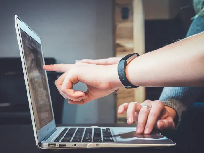 Close view of hands pointing at a laptop while managing business profiles and updating details for local directory listings